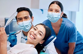 Happy patient posing with her dental care team