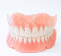 Full upper and lower dentures against light background