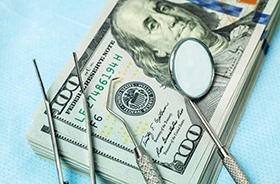 Money and dental tools represent cost of dental emergencies