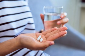 Woman holding pills and water, preparing to take medication?