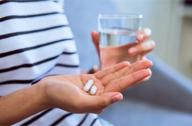 Woman holding pills and water, preparing to take medication?