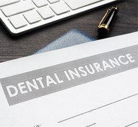 Dental insurance form next to money and computer keyboard