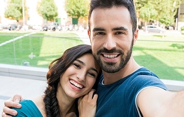 Smiling man and woman outdoors by a field