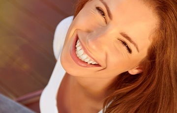 Smiling young woman in white shirt outdoors