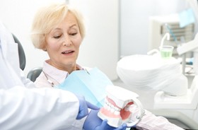 Senior woman learning about implant denture procedure from dentist