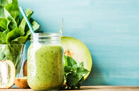 Green smoothie next to kiwi and other produce