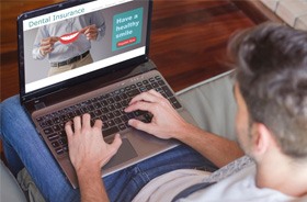 Man using laptop to research dental insurance