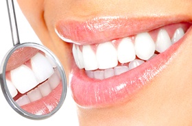Close-up of smile with white teeth beside dental mirror