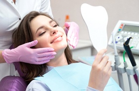 Dental patient using mirror to admire results of cosmetic treatment