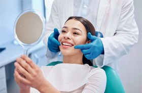 Dental patient smiling at herself in mirror
