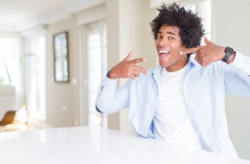 Happy man pointing at his white teeth