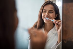 Woman in front of mirror, brushing teeth before breakfast