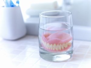 Close-up of upper and lower dentures soaking on bathroom counter