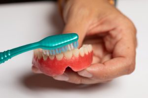 Using soft brush to remove denture stains in Plymouth