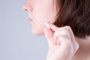 Woman holding extracted tooth next to her cheek