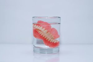 Dentures in glass of liquid on smooth tabletop