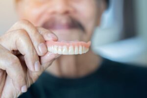 Senior man holding denture for upper arch