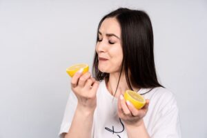 Woman making sour expression while holding a lemon 