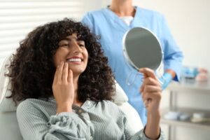 Cosmetic dentistry patient admiring her smile in mirror 