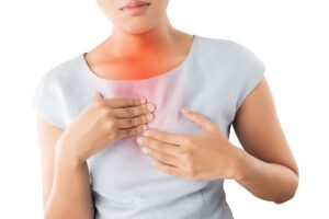 Woman touching her chest as she experiences acid reflux symptoms